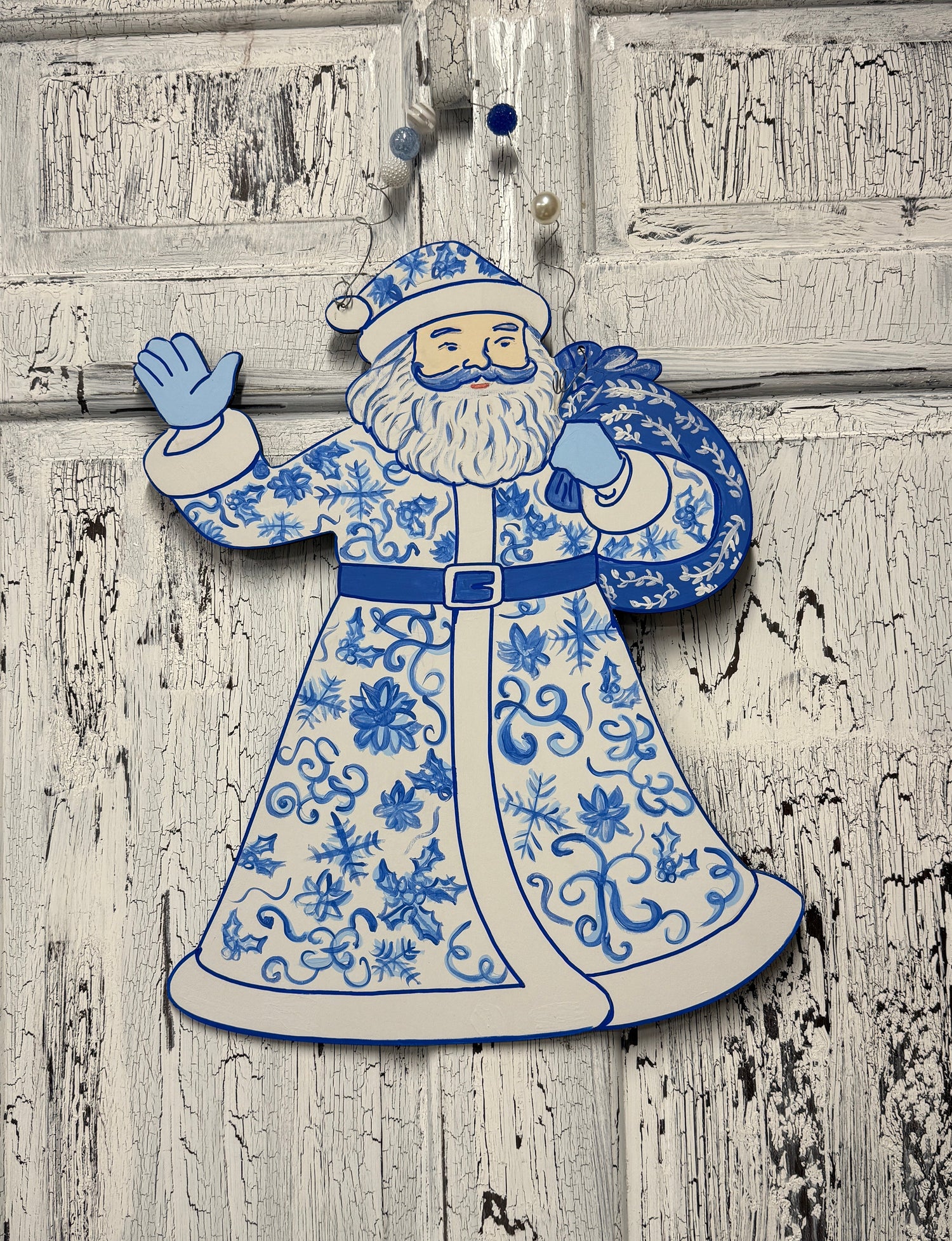 Decorative figure of a traditional Santa Claus in blue and white attire on a wooden background.