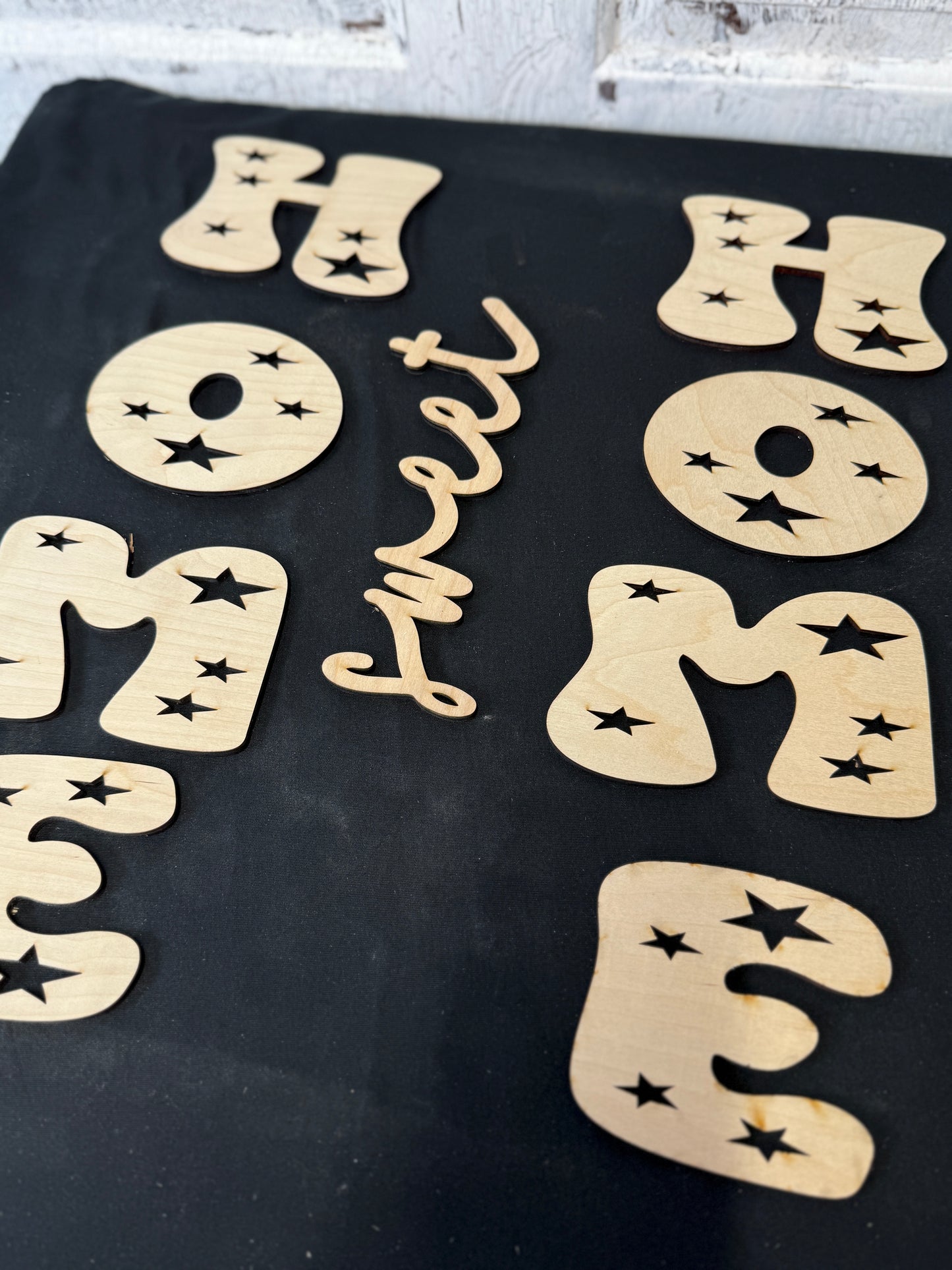 Wooden letters for porch leaner kit spelling 'Home Sweet Home' on a black surface.